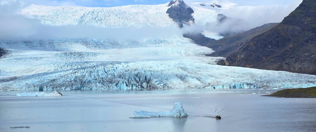 Zodiac boat sailing past an iceberg at Fjallsárlón