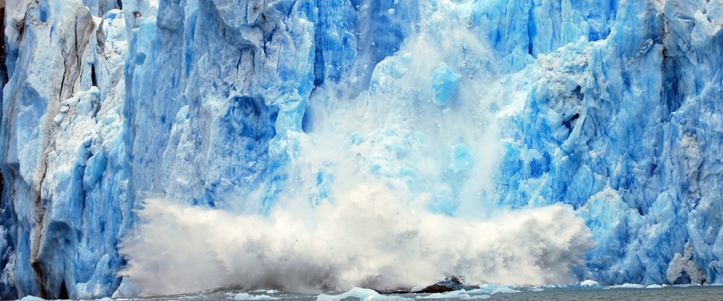 A part of the glacier breaks of and falls into the water with a big splash.