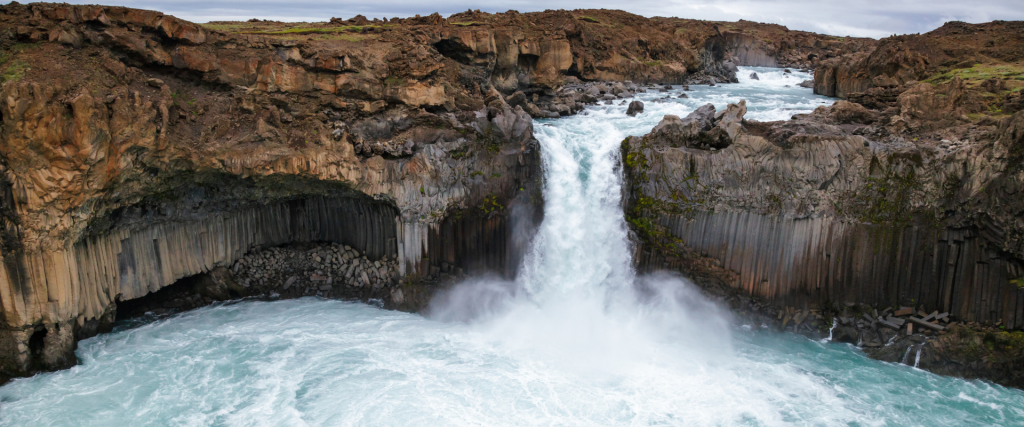 A picture showing Aldeyjarfoss waterfall with basalt rock formations in the backdrop.