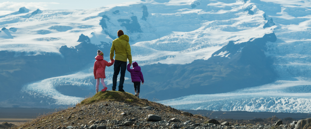 A family standing on a hill overlooking a glacier.